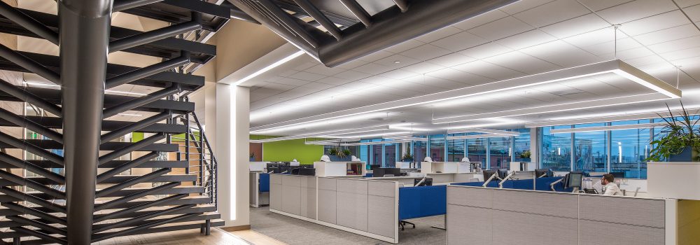 Image of the Alvine Engineering Omaha commercial office. Vantage point features a dynamic staircase and overview of office space featuring warm overhead lighting.
